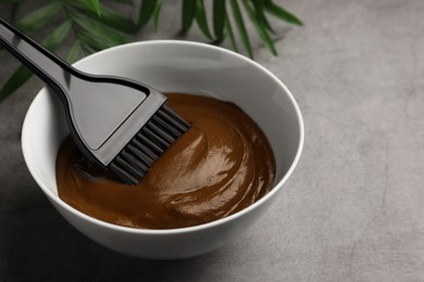 Photo of Bowl of henna cream and brush on light grey table, closeup with space for text. Natural hair coloring