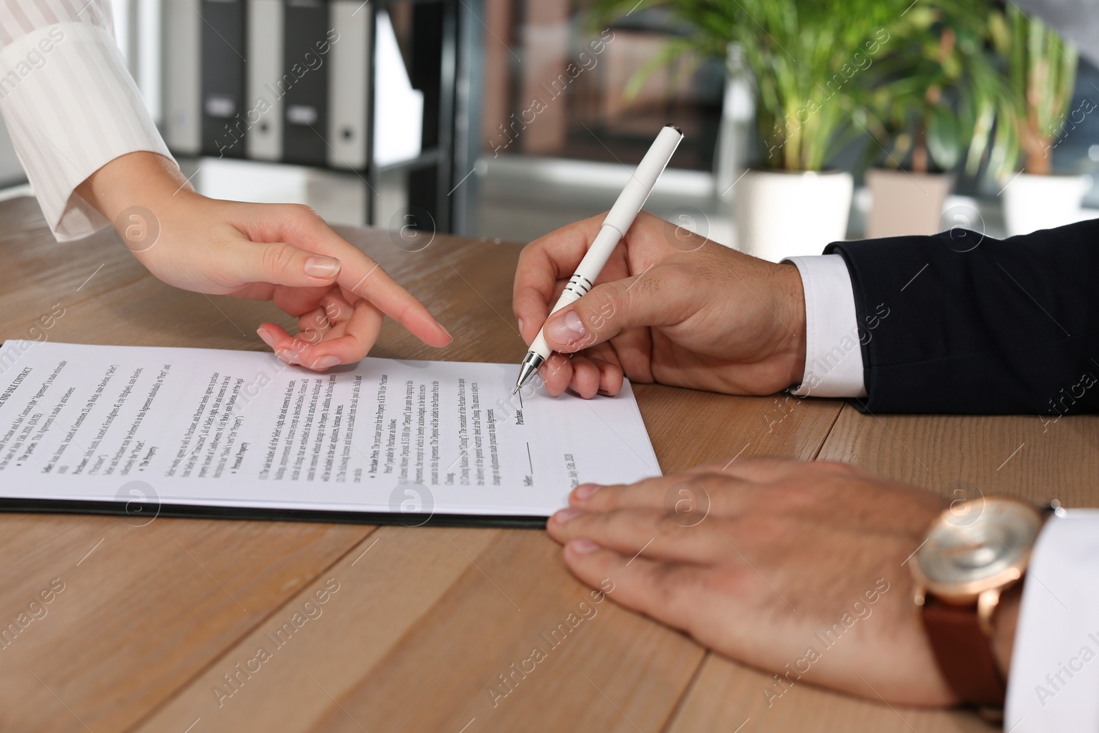 Photo of Businesspeople working with contract at table indoors, closeup