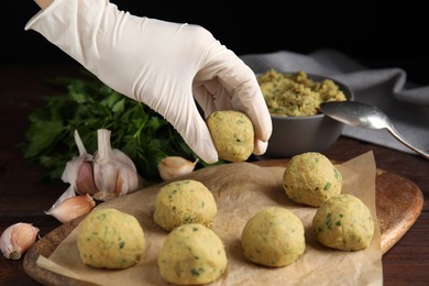 Cook making falafel balls at wooden table, closeup