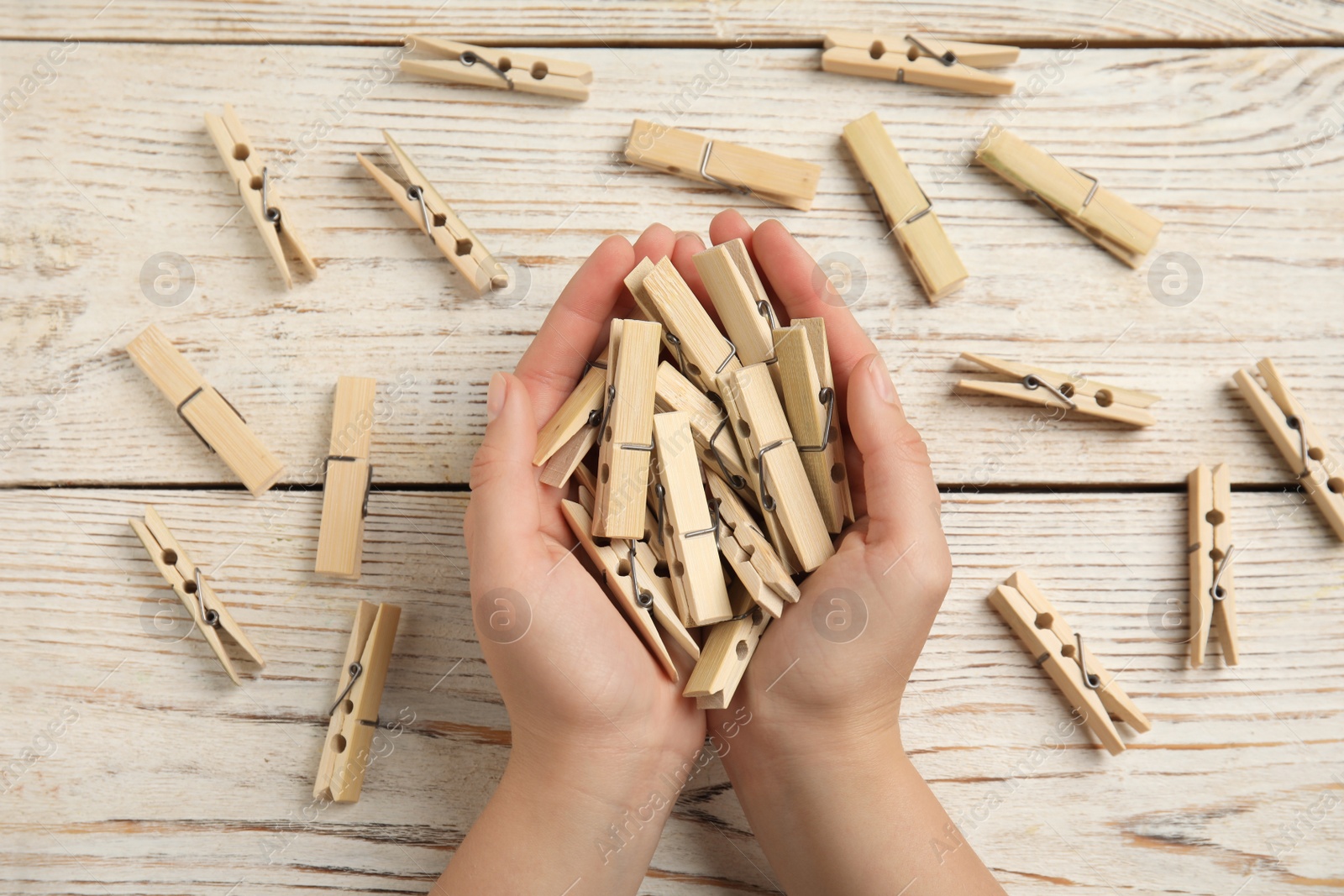 Photo of Woman with clothes pins at white wooden table, top view