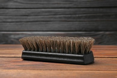 Photo of Shoe brush on wooden table. Footwear care item