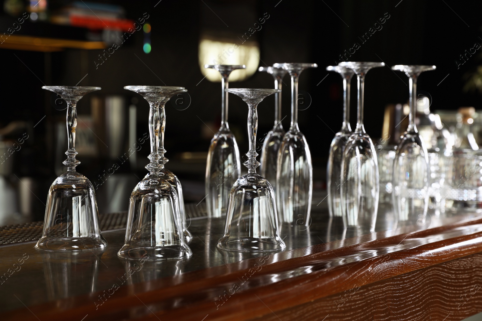 Photo of Different empty clean glasses on counter in bar