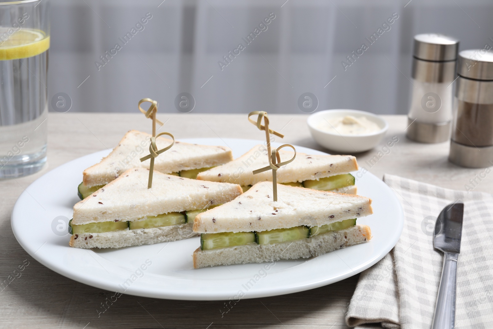 Photo of Tasty sandwiches with cream cheese and cucumber served on white wooden table