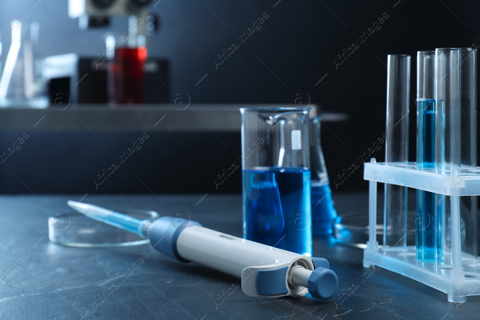 Photo of Laboratory analysis. Micropipette, petri dishes, beaker, flask and test tubes on black table