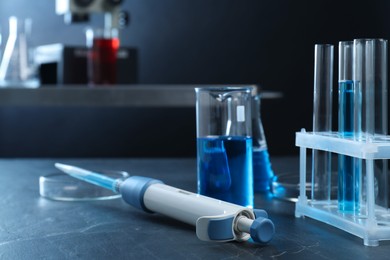 Laboratory analysis. Micropipette, petri dishes, beaker, flask and test tubes on black table