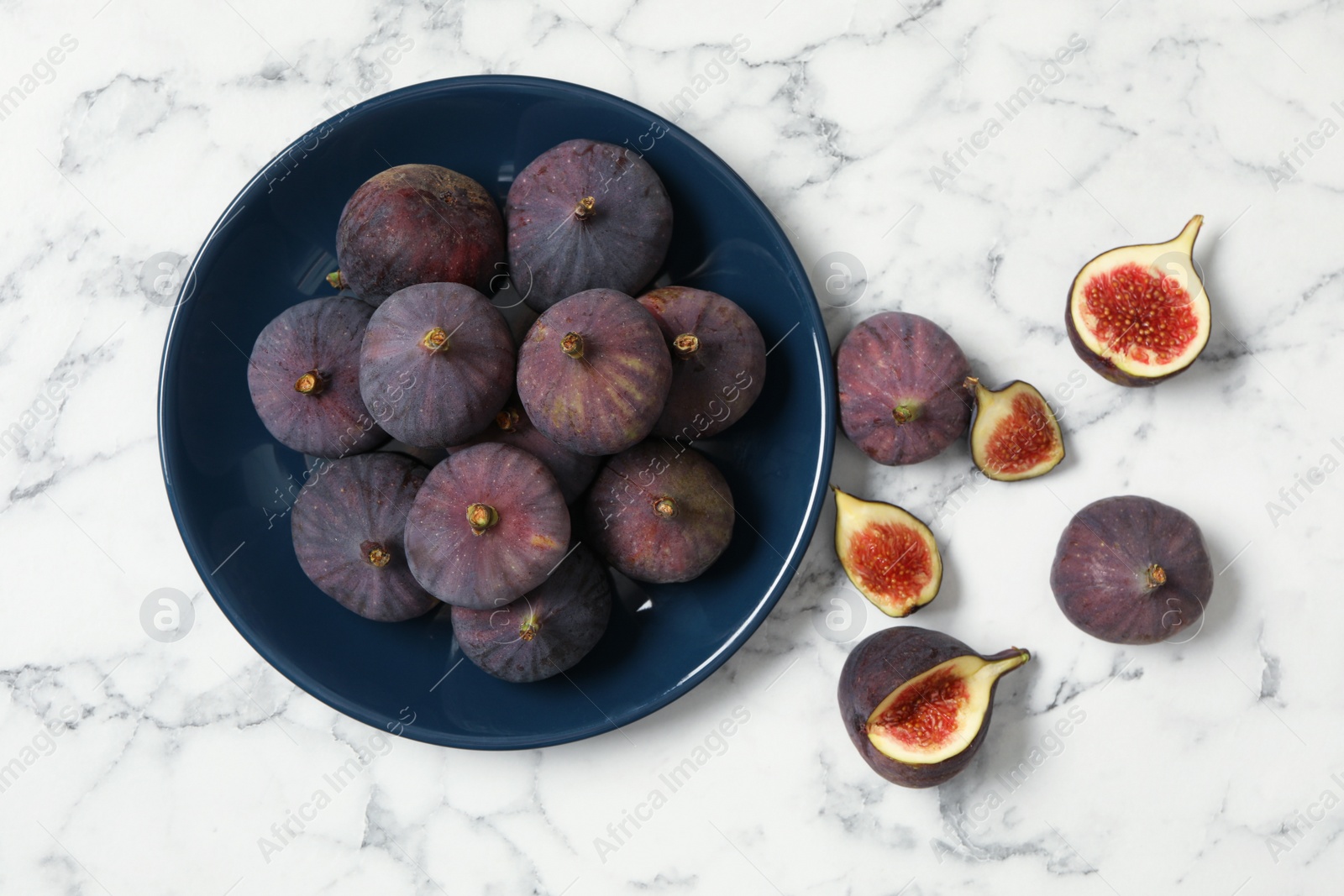 Photo of Whole and cut tasty fresh figs on white marble table, flat lay