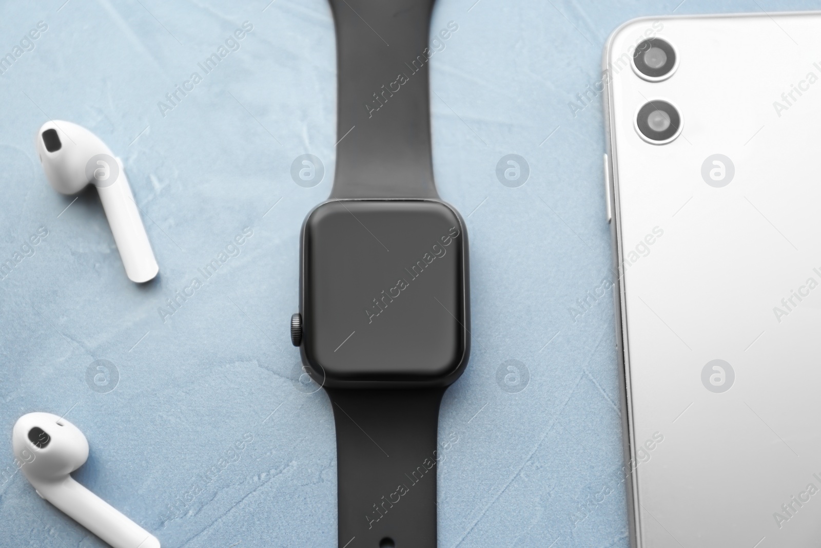 Stylish smart watch, phone and earphones on grey stone table, flat lay Photo of Stylish smart watch, phone and earphones on grey stone table, flat lay