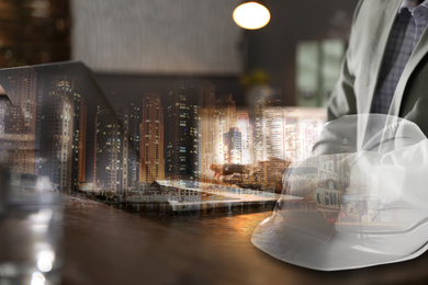 Image of Engineer with laptop at table in office and night cityscape, closeup. Multiple exposure