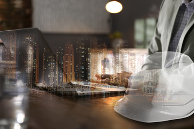 Engineer with laptop at table in office and night cityscape, closeup. Multiple exposure