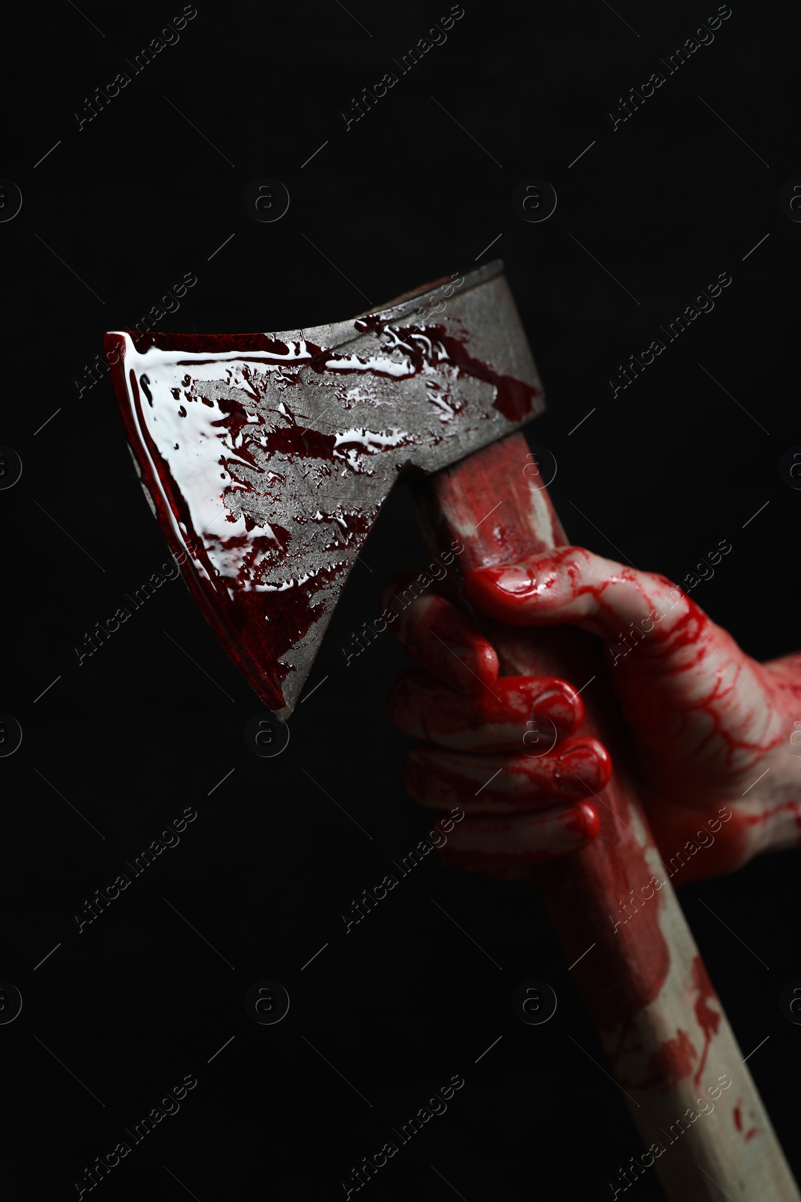 Photo of Man holding bloody axe on black background, closeup