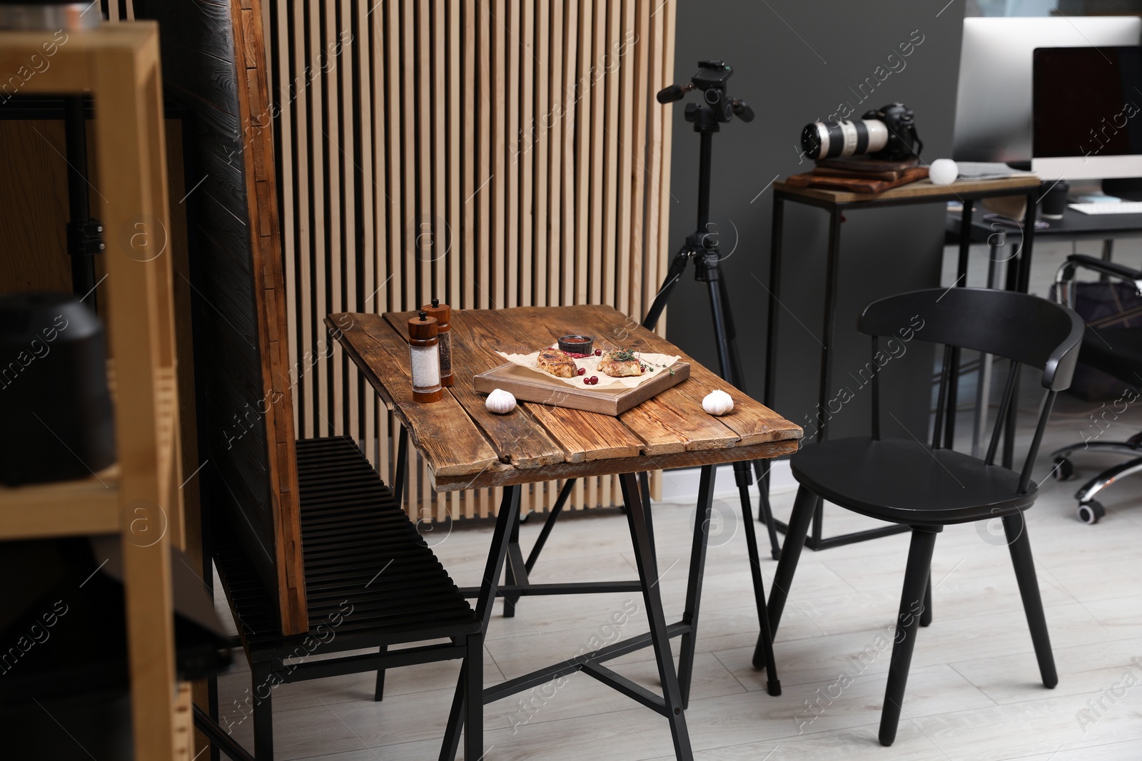 Photo of Professional equipment and composition with delicious meat medallions on wooden table in studio. Food photography