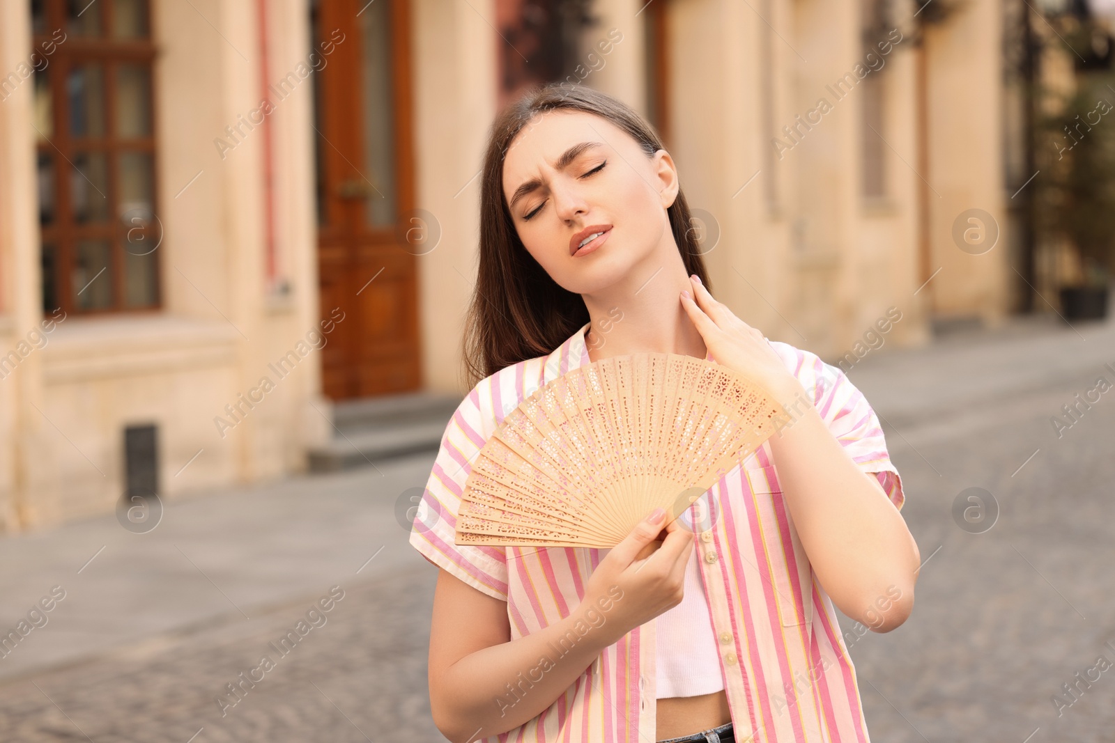 Photo of Woman with hand fan suffering from heat outdoors