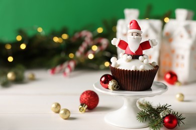 Photo of Tasty Christmas cupcake with Santa Claus figure on white table wooden table. Space for text