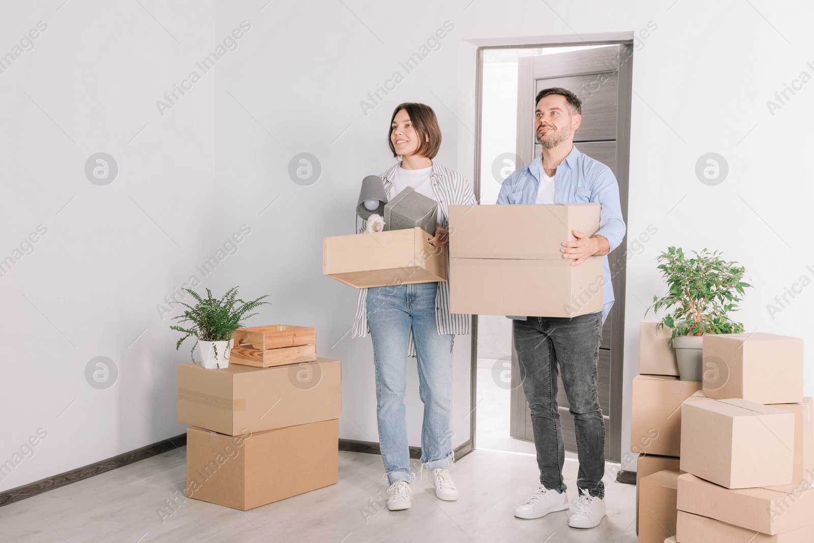 Photo of Happy couple with moving boxes entering in new apartment