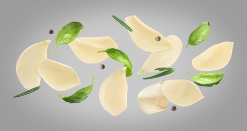 Image of Fresh garlic cloves, basil, peppercorns and rosemary falling on grey background, banner design