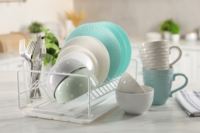 Photo of Many different clean dishware, cups and cutlery on white marble table in kitchen