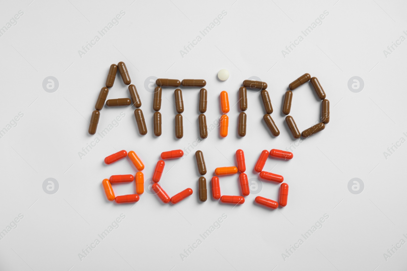 Photo of Words "AMINO ACIDS" made with pills on white background, flat lay
