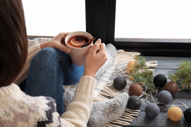 Woman relaxing with hot winter drink near window. Cozy season