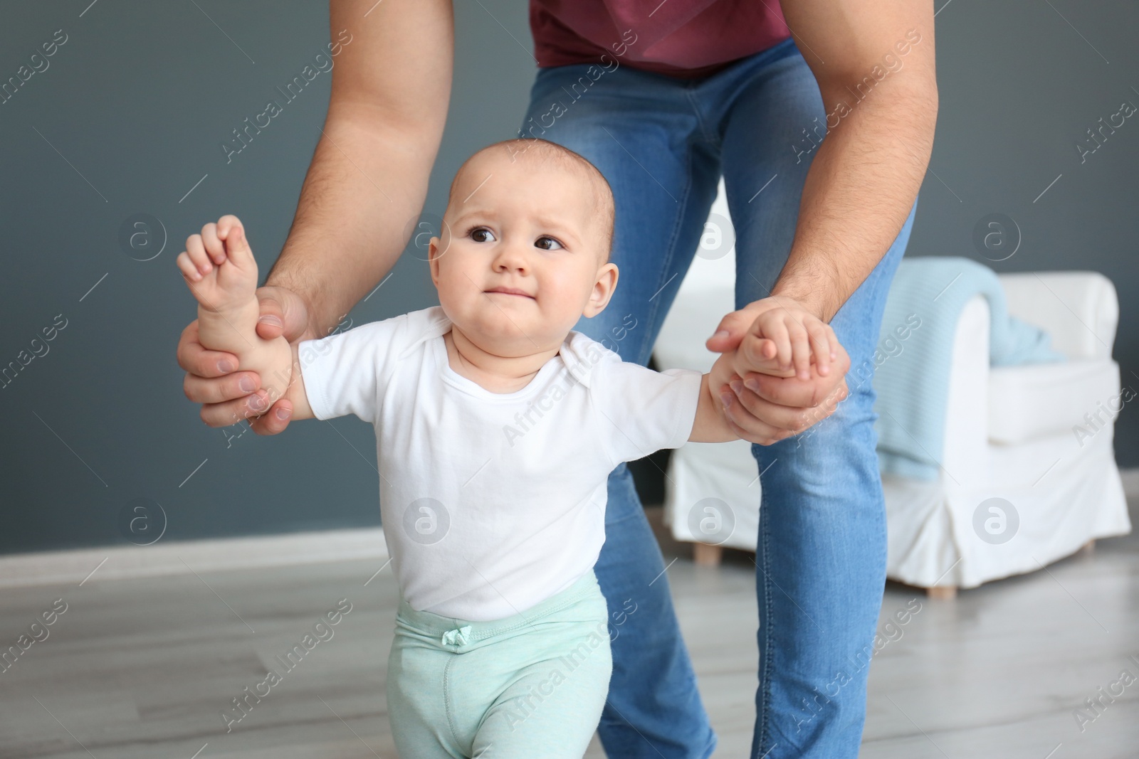 Photo of Baby taking first steps with father's help at home