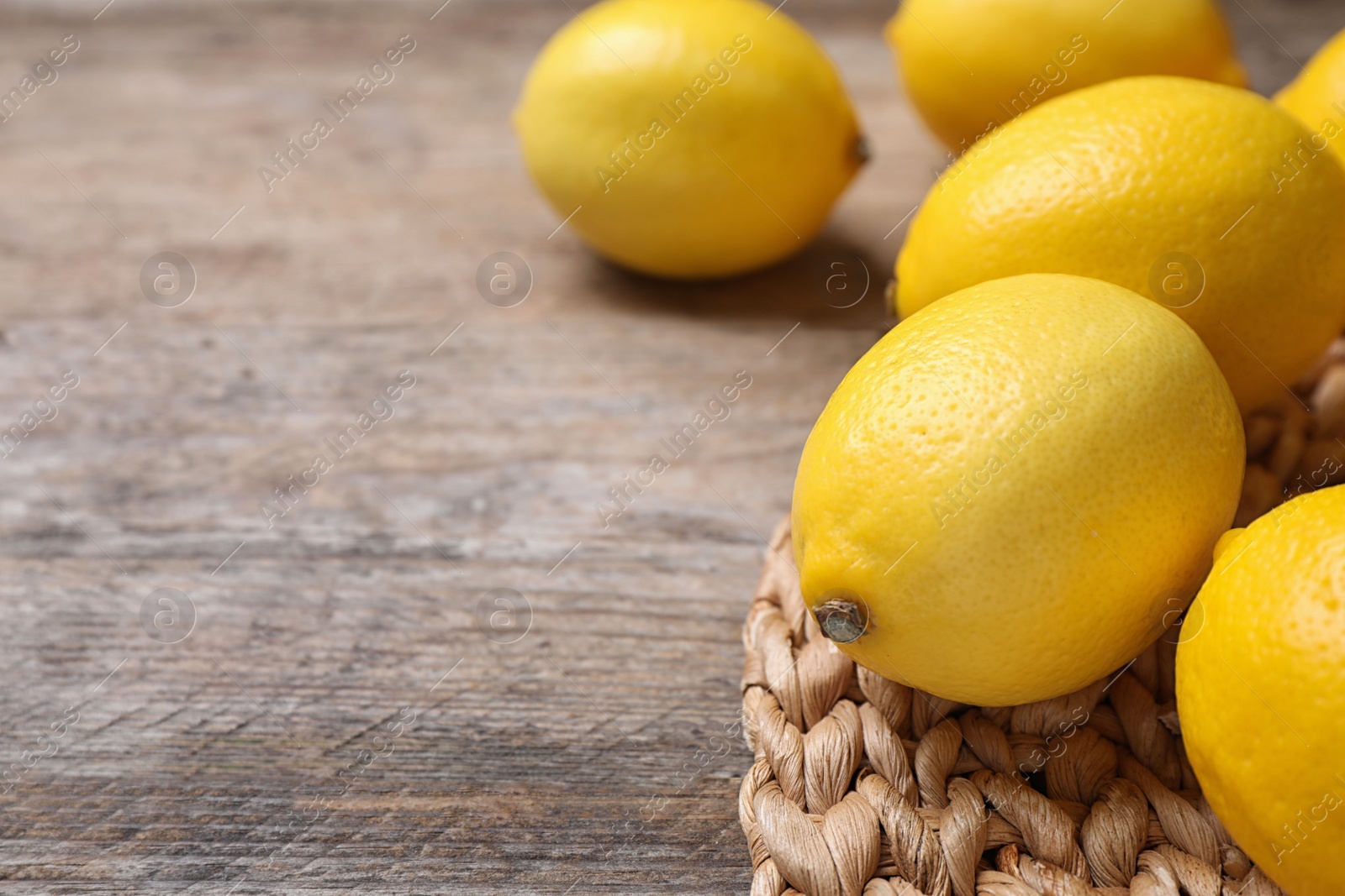 Photo of Fresh ripe lemons on wooden table, closeup. Space for text