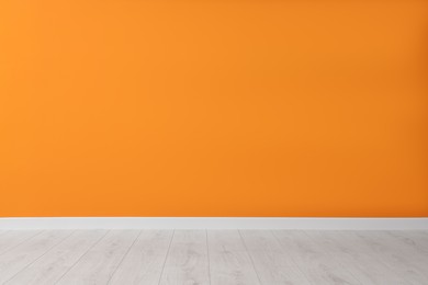 Photo of Empty room with orange wall and wooden floor