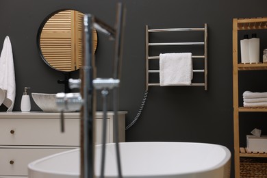 Photo of Stylish bathroom interior with heated towel rail and white tub