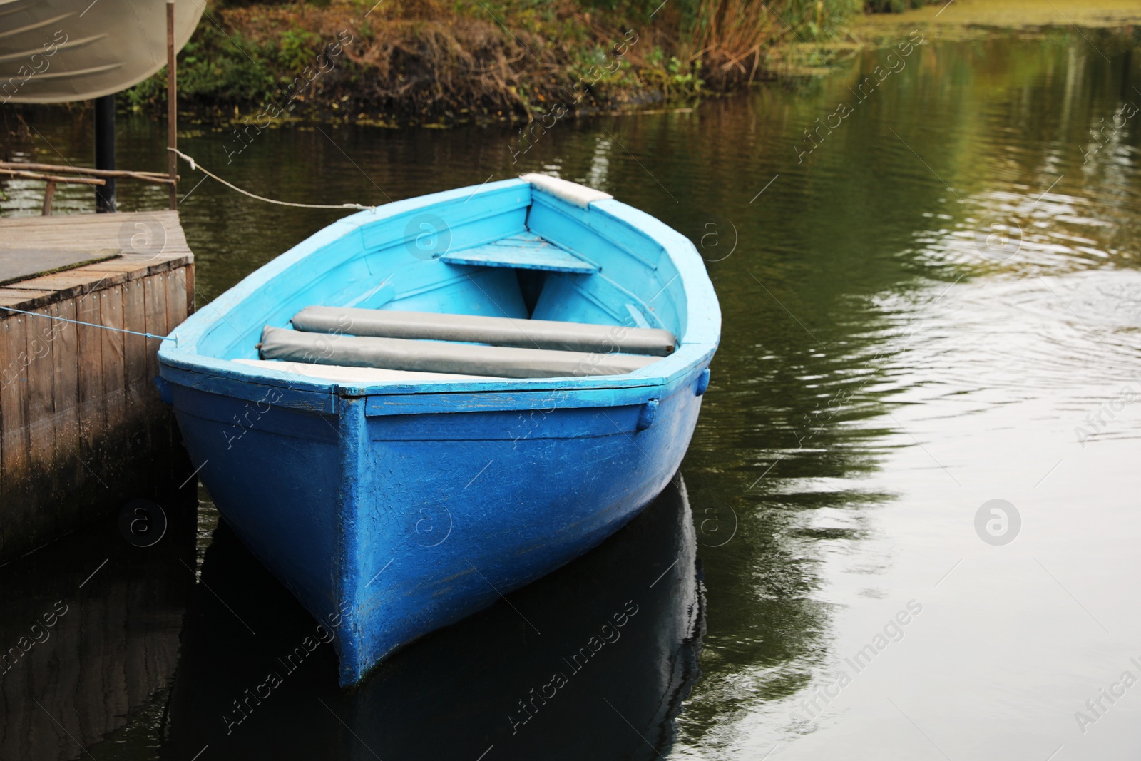 Photo of Light blue wooden boat on lake near pier