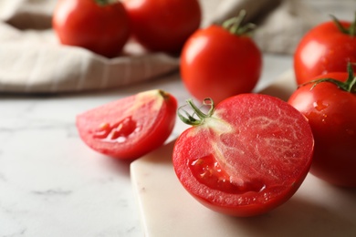 Fresh ripe tomatoes on white marble table, closeup