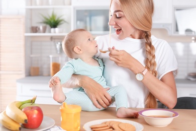 Photo of Woman feeding her child in kitchen. Healthy baby food