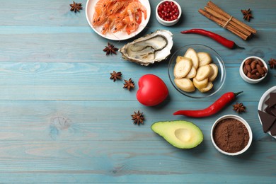 Photo of Natural aphrodisiac. Different food products and heart model on light blue wooden table, flat lay. Space for text