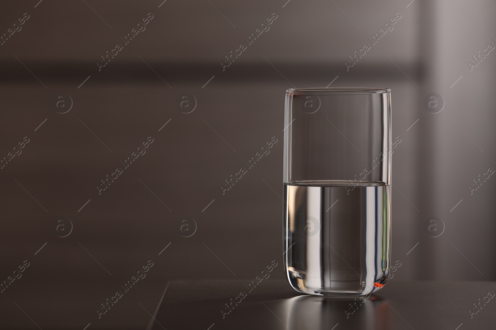 Photo of Glass of pure water on table against blurred background, space for text