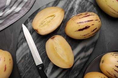 Whole and cut pepino melons on dark table, flat lay