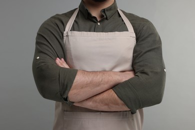 Photo of Man in kitchen apron with crossed arms on grey background. Mockup for design