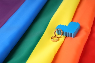 Wedding rings and decorative heart on rainbow flag. Gay marriage