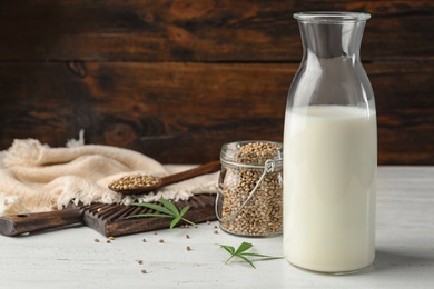 Photo of Composition with bottle of hemp milk on white wooden table. Space for text