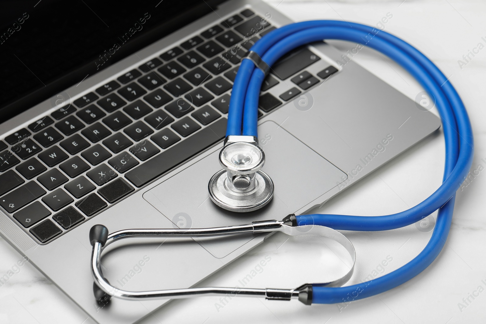 Photo of Stethoscope and modern laptop on white table