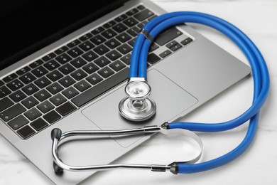 Stethoscope and modern laptop on white table