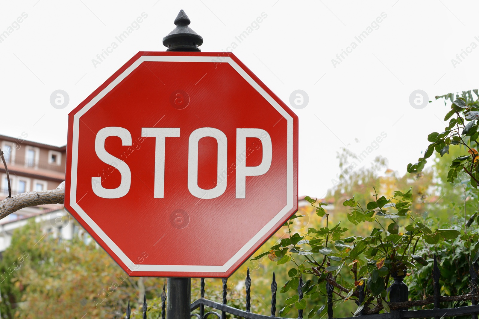 Photo of Post with Stop sign near metal fence outdoors