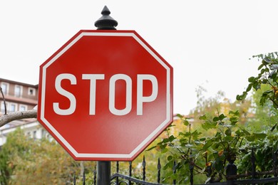 Post with Stop sign near metal fence outdoors
