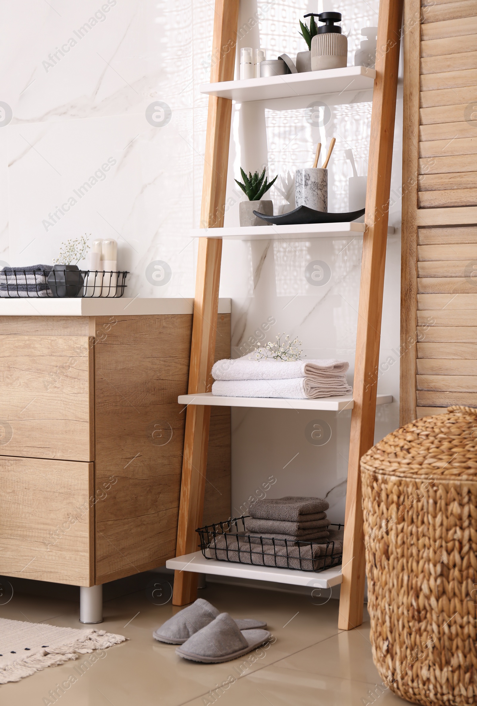 Photo of Soft towels and different toiletries on decorative ladder in bathroom. Interior design