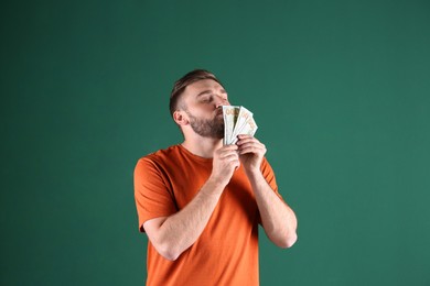 Greedy young man sniffing money on green background