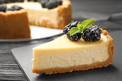 Piece of delicious cheesecake decorated with blackberries on table