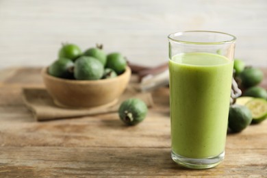 Photo of Fresh feijoa smoothie in glass on wooden table, closeup. Space for text