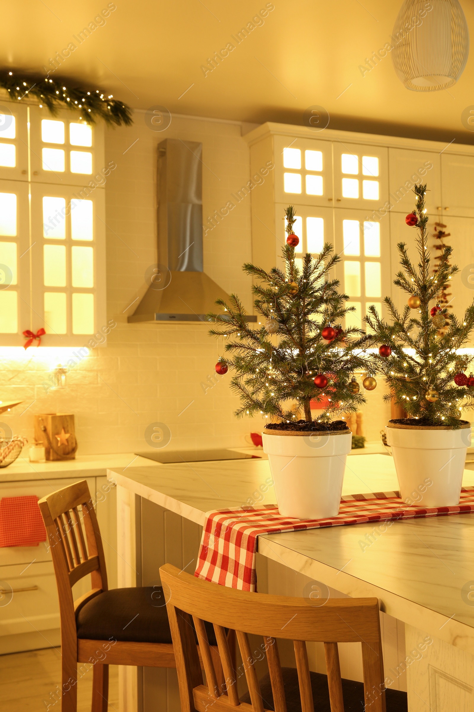 Photo of Small Christmas trees and festive decor in kitchen