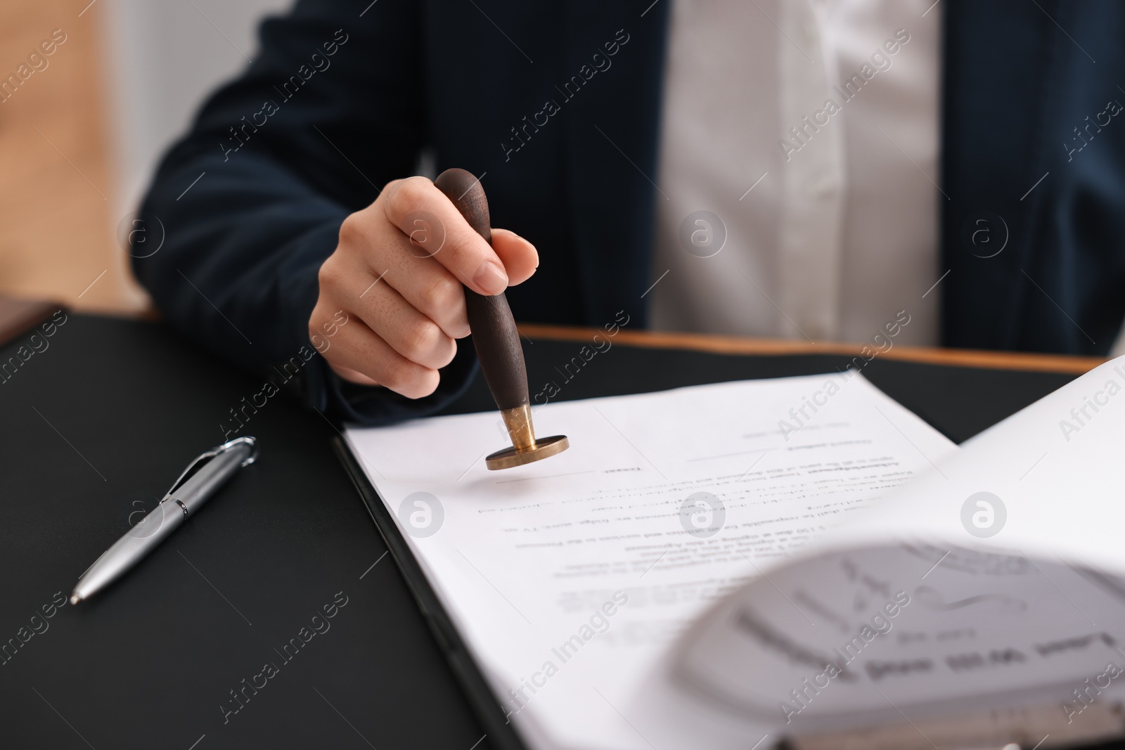 Photo of Notary sealing document at table in office, closeup