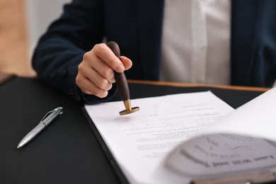 Photo of Notary sealing document at table in office, closeup