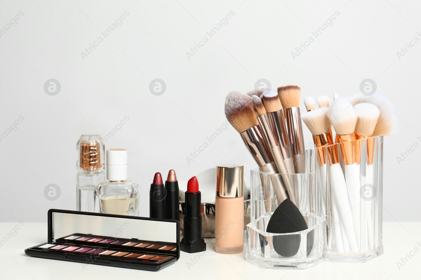 Photo of Set of cosmetic products and makeup brushes on dressing table