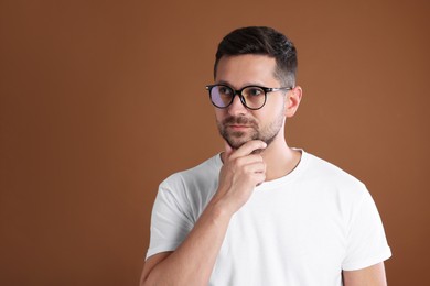 Photo of Portrait of man in stylish glasses on brown background. Space for text