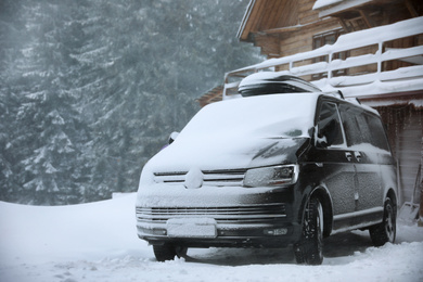 Modern car covered in snow outdoors on winter day