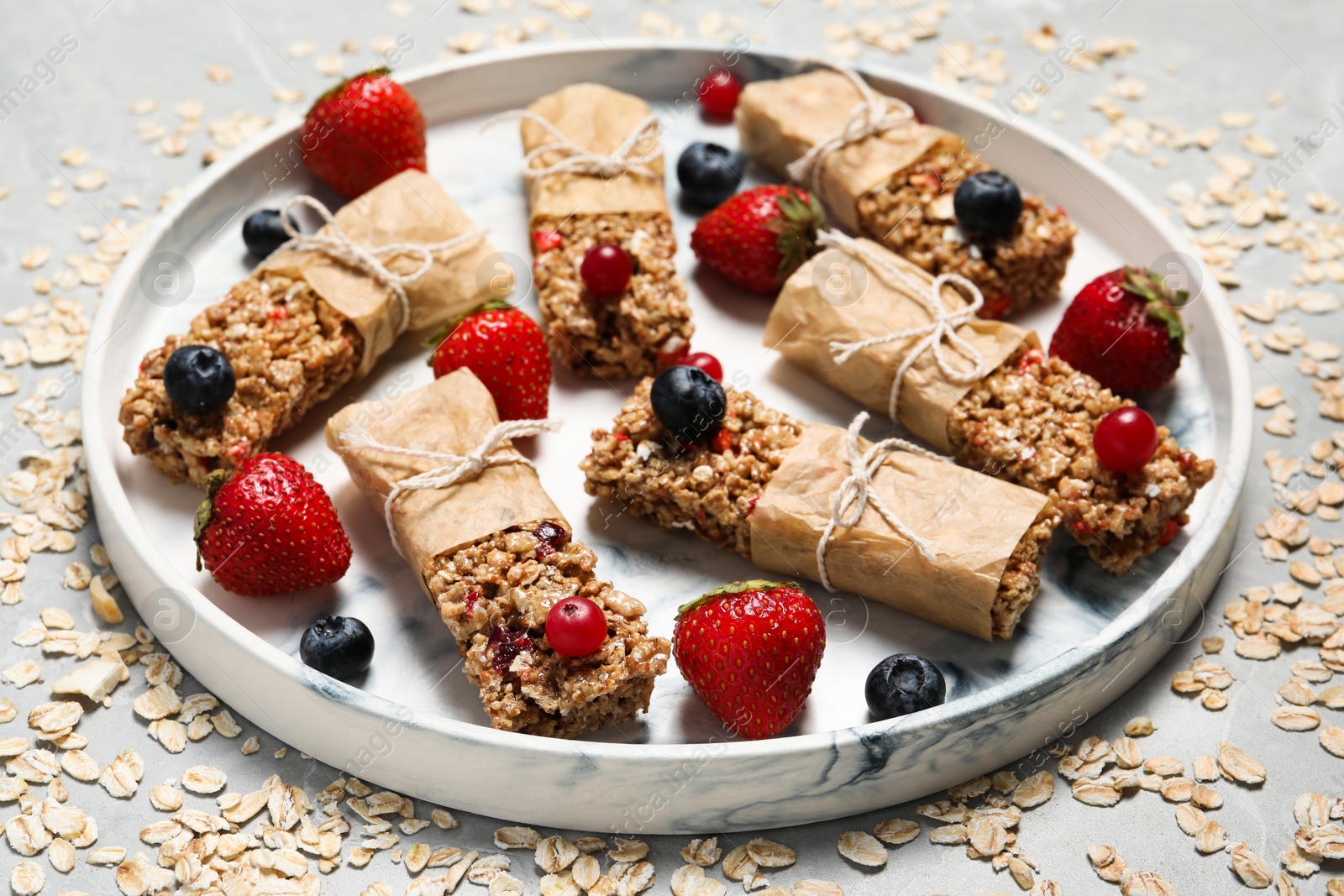 Photo of Tasty granola bars and ingredients on light table